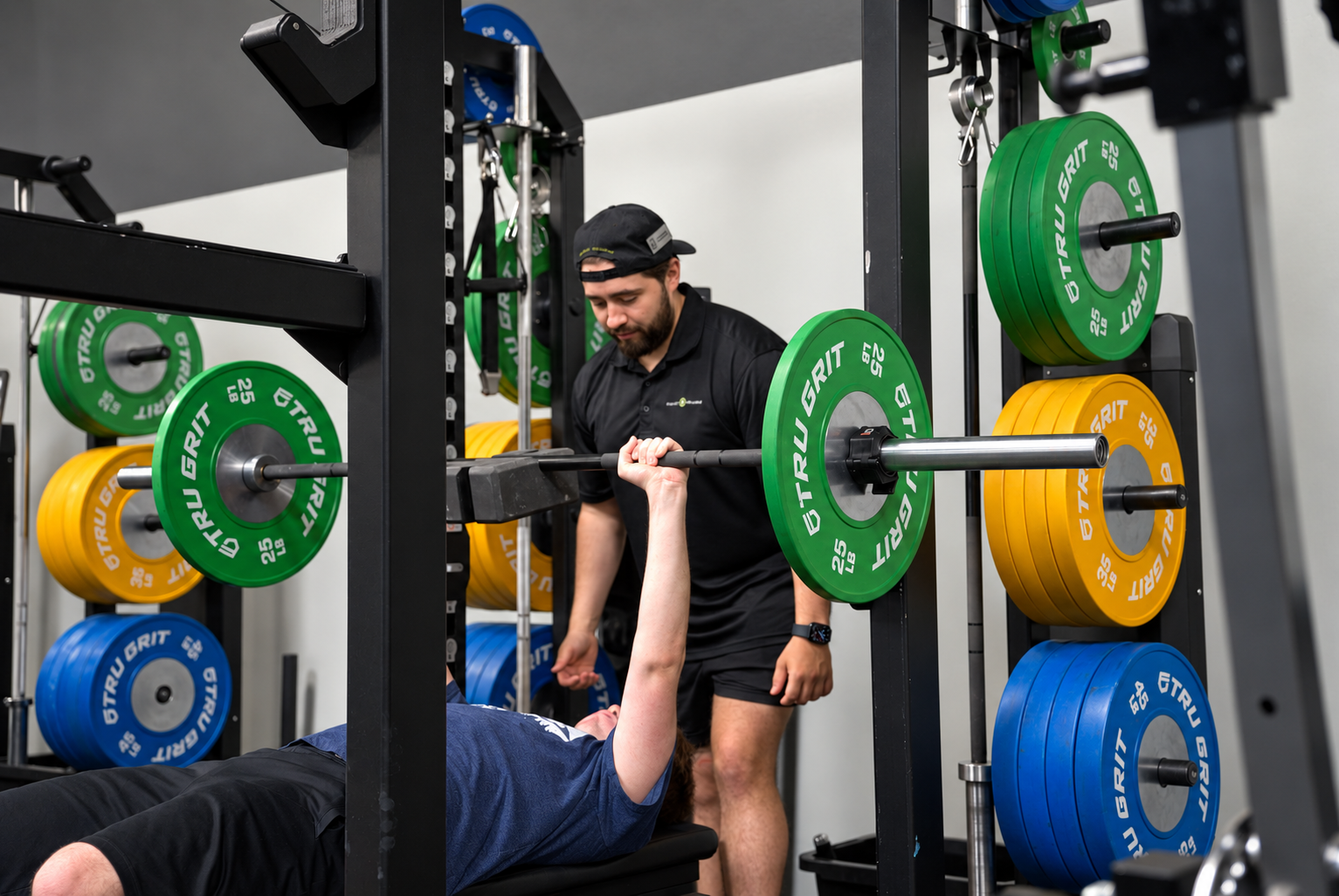 Project Wellbeing coach spotting a member through a bench press